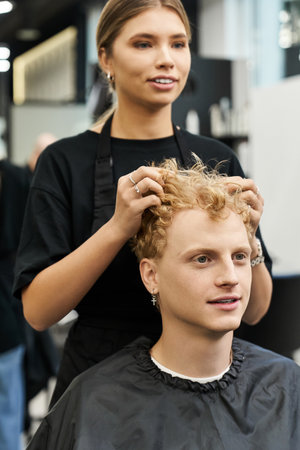 A stylist enhances a clients curls, showcasing modern beauty trends in a chic salon.の写真素材