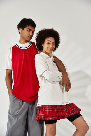 A young couple stands close, radiating love and style in a minimalistic environment.