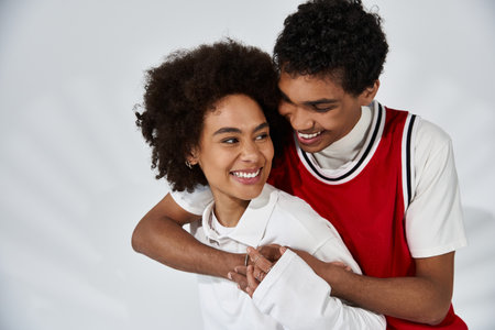 Two young lovers express affection, showcasing their style and happiness in a bright environment.