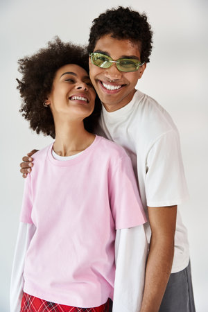 Young couple shares joyful smiles and embraces, radiating love and happiness in a bright space.