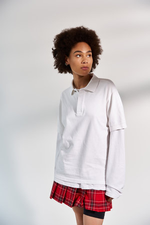 A young woman posing on white backdrop while in stylish sporty attire.