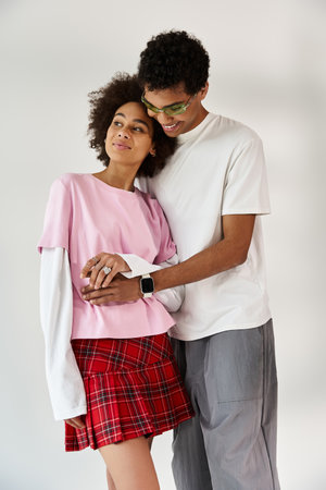 A stylish young couple embraces warmly in front of a minimalistic backdrop.