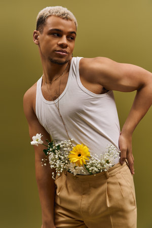 A young African American man poses confidently with vibrant flowers in a trendy studio environment.の写真素材