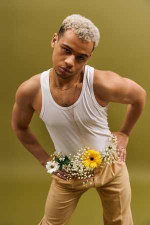 Handsome African American man poses confidently in a tank top surrounded by beautiful flowers.の写真素材