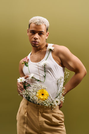 Brightly dressed young man with dyed white hair and flowers models his unique style in studio light.の写真素材