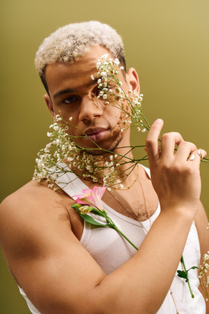 A young african american man showcases his unique style while holding flowers in a vibrant studio.の写真素材
