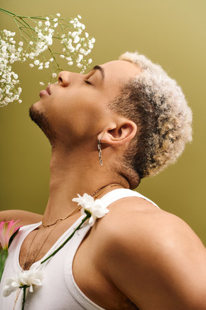 A stylish young african american man poses gracefully with flowers in a modern studio.