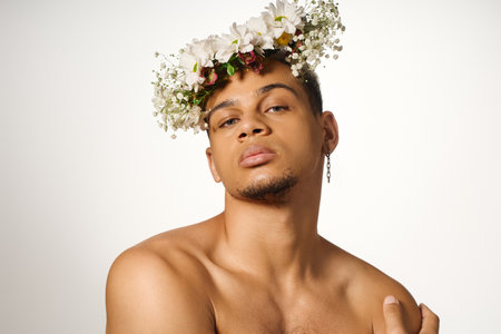 A young shirtless African American man poses confidently in a studio, adorned with flowers.の写真素材
