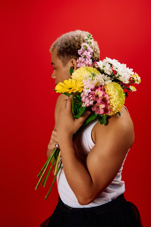 A stylish young Black man confidently displays a vibrant bouquet of flowers.の写真素材
