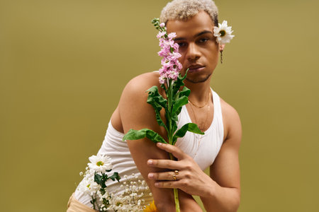 A stylish young man poses with flowers in a studio, showcasing modern fashion trends.の写真素材