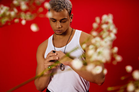 A young man with dyed hair poses confidently in a tank top, surrounded by a striking red backdrop.