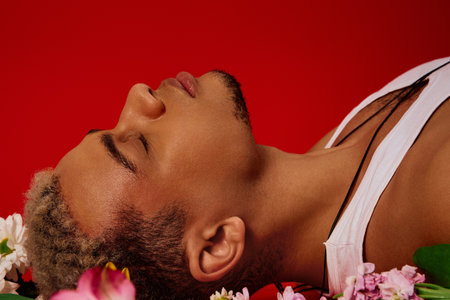 A young african american man leans back in a vibrant red studio, exuding a cool, fashionable vibe.の写真素材