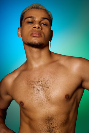 A muscular young African American man poses confidently shirtless against a colorful backdrop.の写真素材