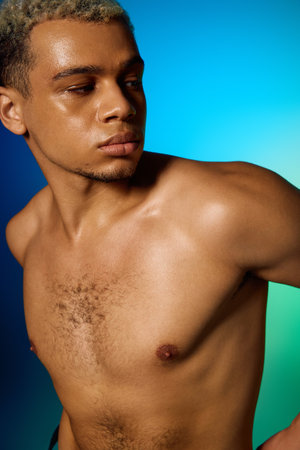 A young, shirtless African American man poses confidently in a studio with colorful lights.の写真素材