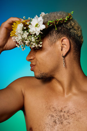 Muscular young man expresses individuality with dyed hair and a floral crown in a studio setting.の写真素材