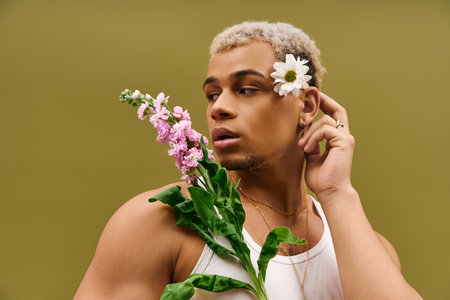 A young and stylish African American man poses gracefully with flowers, showcasing modern fashion.の写真素材