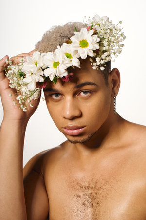 A shirtless man poses elegantly with natural flowers in a bright studio, exuding charisma and style.の写真素材