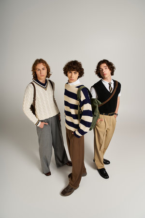 Three young friends display their individual styles while posing confidently together indoors.