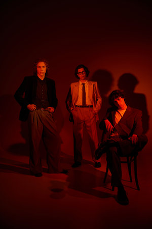 Three young men display their individual styles against a warm, dramatic background.