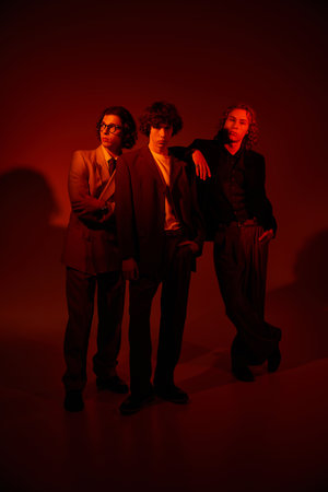 Three young men express their individuality through fashion in a vibrant atmosphere with warm tones.の写真素材