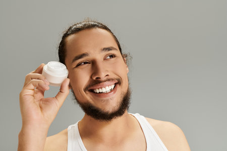 A handsome young bearded man enjoys a moment of joy, showcasing skincare as he smiles cheerfully.の写真素材