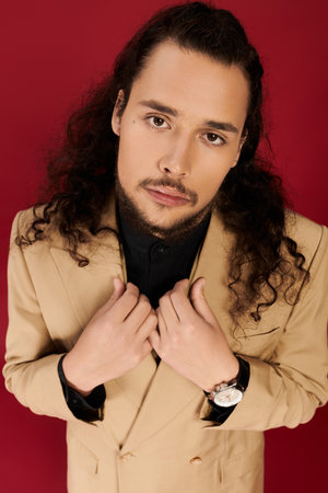 Young man with curly hair and beard presents a confident look while dressed elegantly.