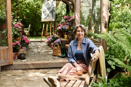 A confident senior woman relaxes in her lovely, flower filled garden.の写真素材