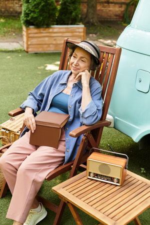 A senior woman relaxes in a garden chair, surrounded by greenery and vintage charm.