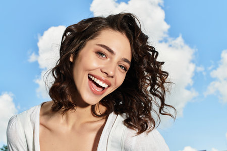A pretty young woman with wavy brown hair enjoys the outdoors on a bright summer day.