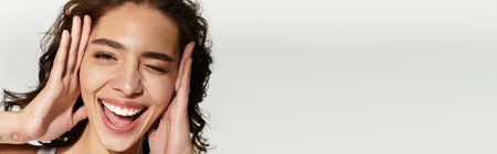 A joyful woman with lovely makeup poses in a studio, radiating youth and confidence, bannerの写真素材