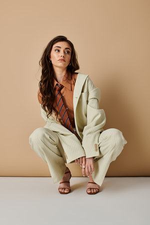 A beautiful young woman with long brown hair poses fashionably in a studio.の写真素材