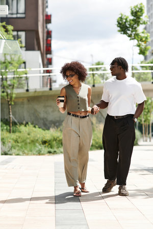 Stylishly dressed couple walks together, sharing a warm moment in the bustling city.