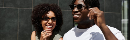 A young African American couple shares smiles and laughter while on a casual summer date, banner