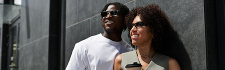 A young couple dressed in trendy outfits shares laughter while exploring the urban landscape, bannerの写真素材