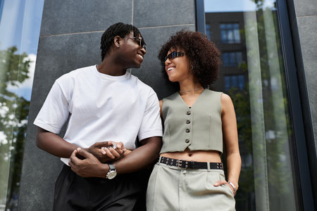A young African American couple embraces each other, sharing smiles in the city during summer.の写真素材