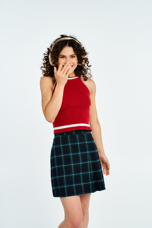 A young woman with curly hair poses confidently in a fashionable outfit and headphonesの写真素材