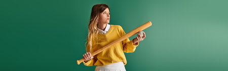 Excited young woman enjoys a summer day, holding a baseball bat and ball, ready to play.の写真素材