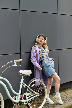 A stylish young woman in a vibrant outfit stands beside her bicycle, enjoying the warmth of summer.