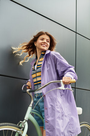 A young beautiful woman enjoys a sunny day while riding a bicycle in an urban setting.の写真素材