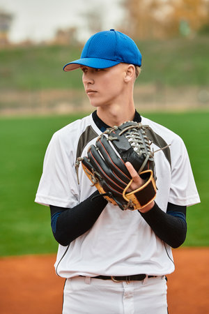 A confident player stands ready on the field, eager to pitch as the sun sets behind him.