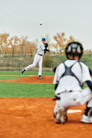 Two teenage boys passionately play baseball, with one pitching and the other ready to catch.の写真素材