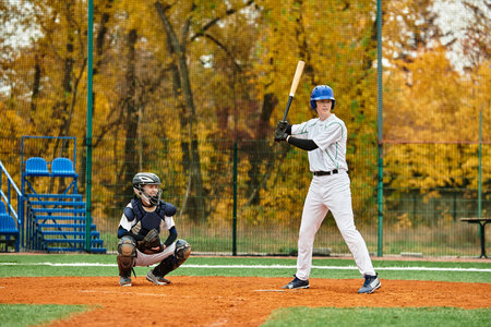 Two teenage boys play baseball intensely on a vibrant field surrounded by colorful leaves.の写真素材