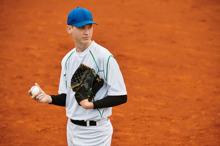 A confident player eagerly showcases his skills on a reddish baseball field.