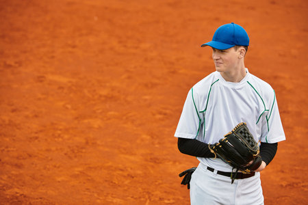 A cheerful player with a bright smile stands on an orange baseball field, ready to play.