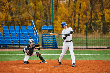 Two teenage boys engage in an exciting baseball match surrounded by vibrant autumn foliage.