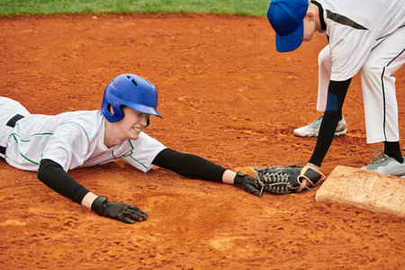 Two boys excitedly compete for a base in a friendly baseball game on a sunny day.の写真素材