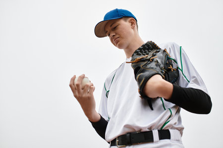 Teenage boy holds a baseball, showcasing focus and determination before the pitch.の写真素材