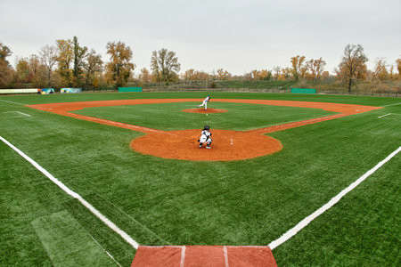 Two teenage boys compete fiercely in a baseball game on a vibrant green field as autumn leaves fall.