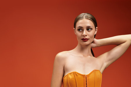 Radiant and poised, a young beautiful woman showcases her fashion sense in a stunning orange dress.の写真素材