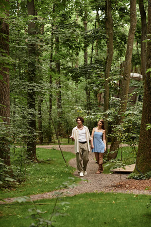 A young couple walks hand in hand, surrounded by lush greenery and natures tranquility.の写真素材
